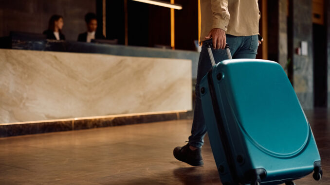Close up of man with suitcase walking into a hotel.